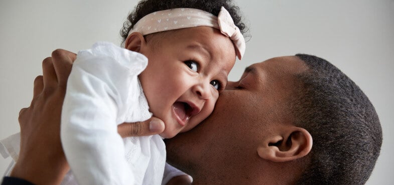 Father kissing smiling baby